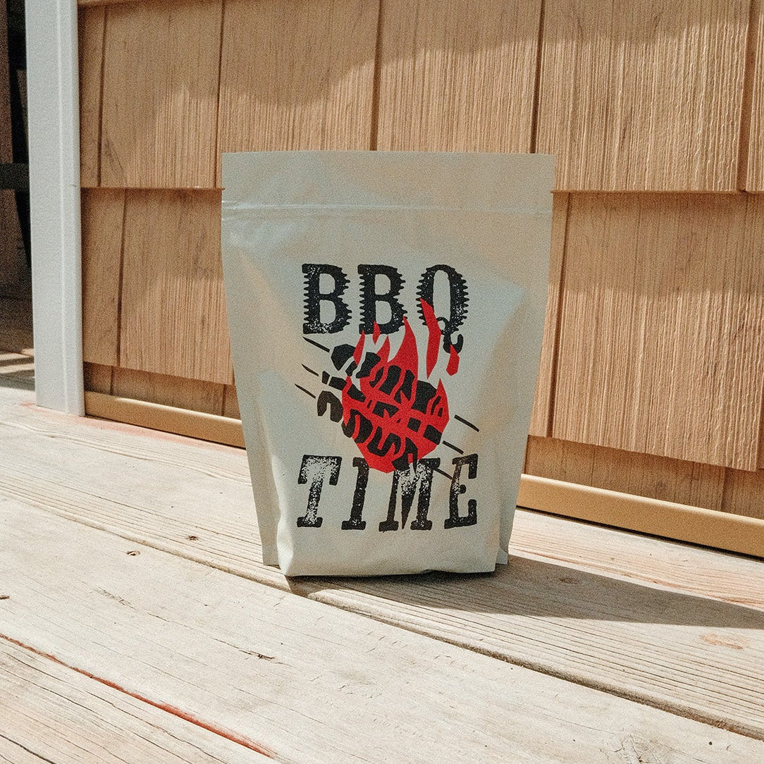 Bag labeled 'BBQ Time' on a wooden deck with a wooden wall in the background