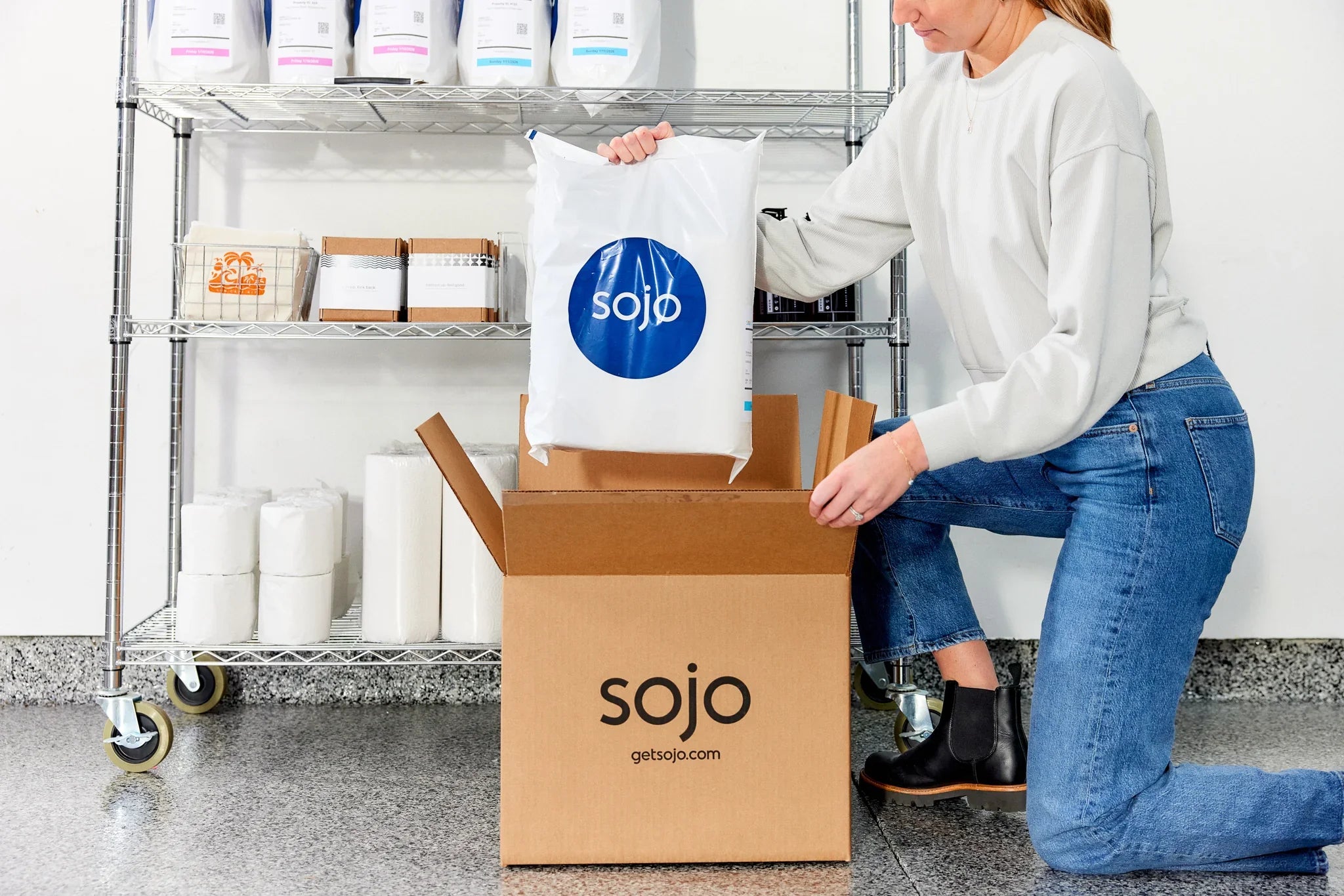 Woman putting Sojo branded packaging into a Sojo branded box.