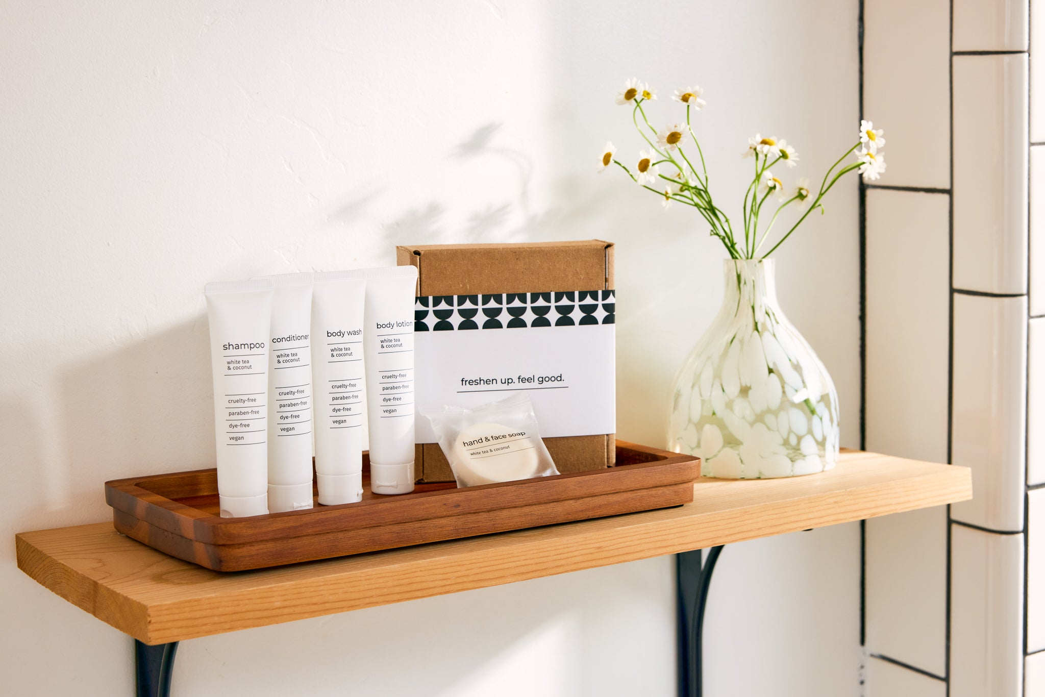 Minimalist bathroom shelf with cruelty-free toiletries kit and white vase with daisies