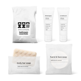 Bathroom essentials kit with shampoo, conditioner, body bar soap, and hand and face soap in a bag.