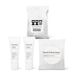 Full bath amenity essentials kit featuring shampoo, body wash, and hand and face soap in a bag.
