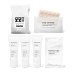Bathroom amenities kit including shampoo, conditioner, body lotion, body bar soap, and makeup wipe in a bag.