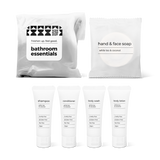 Bathroom essentials kit with shampoo, conditioner, body wash, body lotion, hand and face soap in a bag.