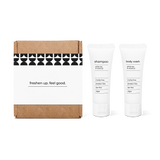 Bathroom amenities kit featuring shampoo and body wash in travel-size bottles in a box.