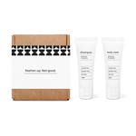 Bathroom amenities kit featuring shampoo and body wash in travel-size bottles in a box.